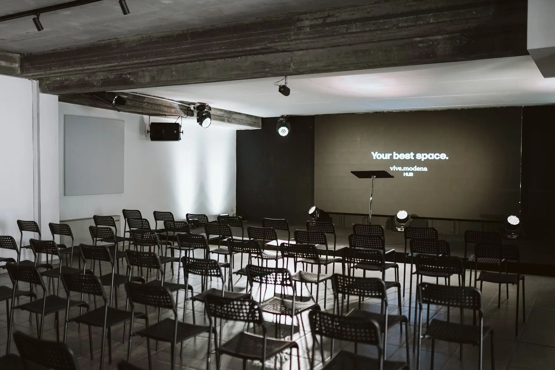 Sala conferenze con file di sedie nere davanti a uno schermo con la scritta "Your best space."