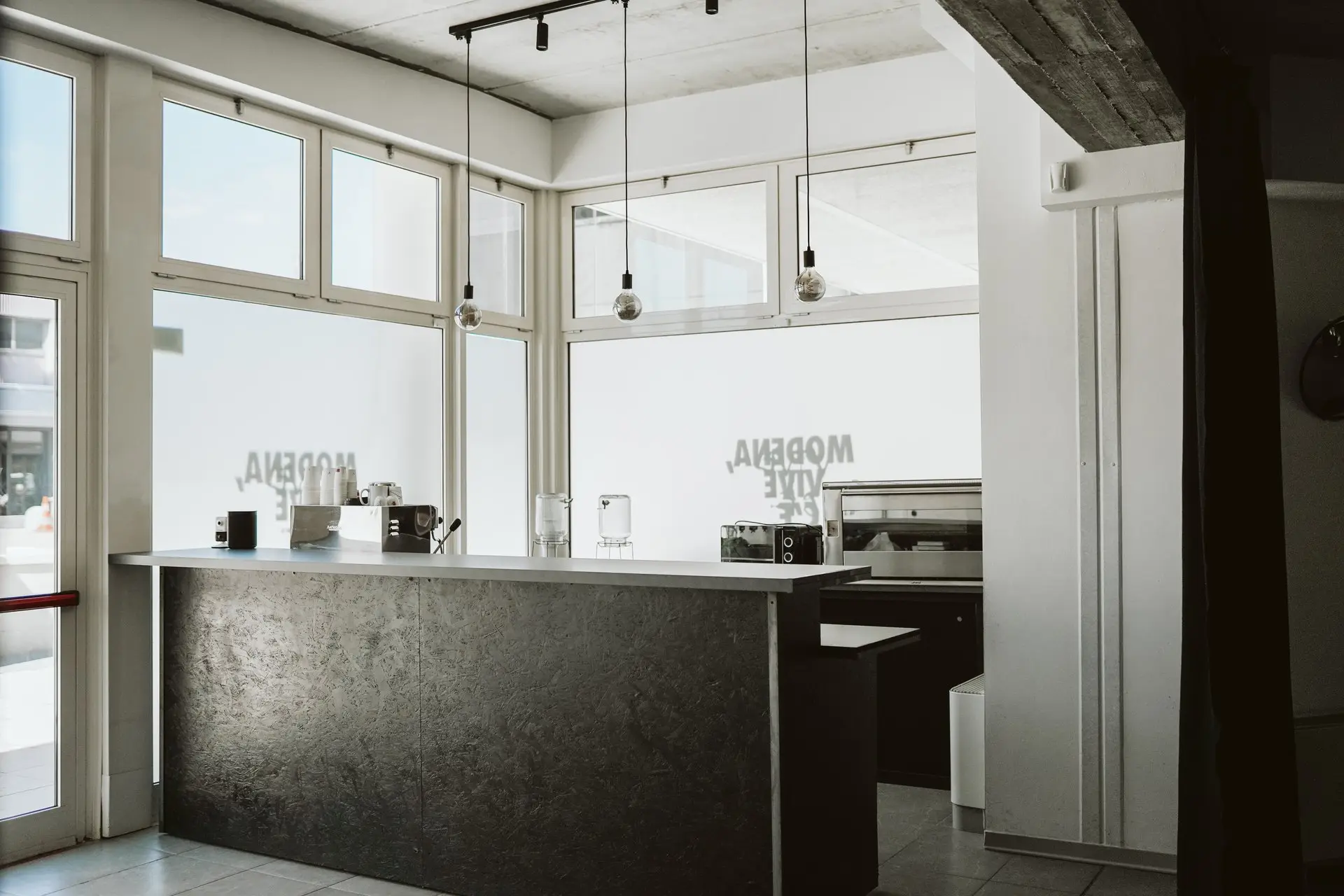 Interno di caffetteria moderna con bancone scuro e grandi vetrate